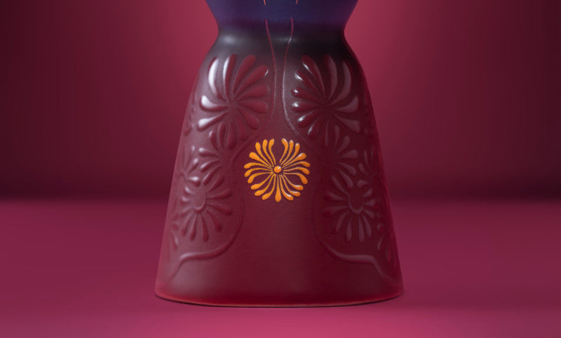マゼンタのデキャンタ底部に描かれた花々と金色のモチーフ